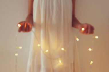 Garland Noel ışıkları tutan genç kadın soyut ve bokeh görüntüsünü.