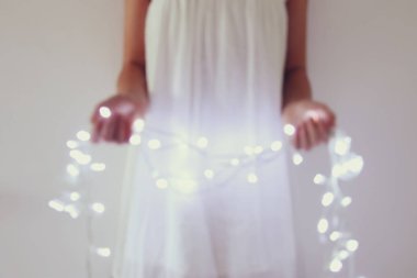 Garland Noel ışıkları tutan genç kadın soyut ve bokeh görüntüsünü.