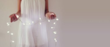 Garland Noel ışıkları tutan genç kadın soyut ve bokeh görüntüsünü.