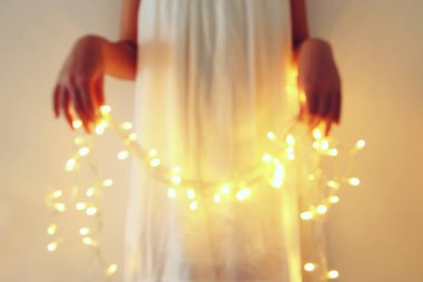 Garland Noel ışıkları tutan genç kadın soyut ve bokeh görüntüsünü.