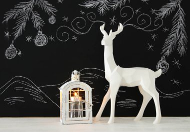 Ahşap masa üzerinde el ile kara tahta arka plan üzerinde beyaz Ren geyiği tebeşir illüstrasyonlar çizilmiş.