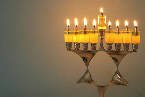 image of jewish holiday Hanukkah background with menorah (traditional candelabra) and burning candles.