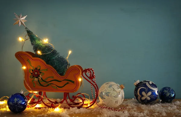 Afbeelding van de kerstboom op de houten oude slee over besneeuwde houten tafel. — Stockfoto
