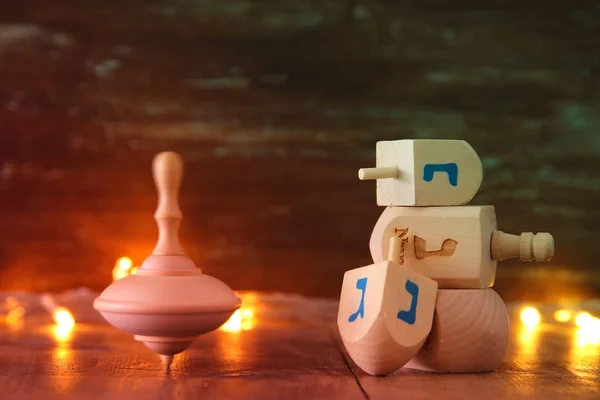 Vacaciones judías Hanukkah con la colección dreidels de madera (peonza) y luces de guirnalda de oro en la mesa —  Fotos de Stock