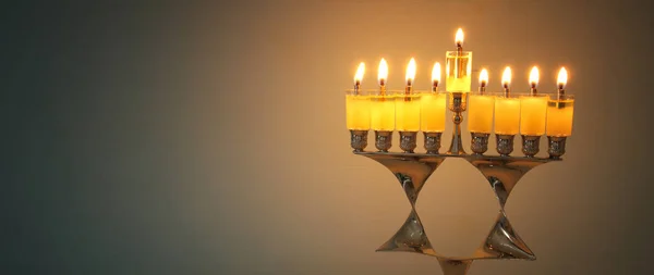 image of jewish holiday Hanukkah background with menorah (traditional candelabra) and burning candles.