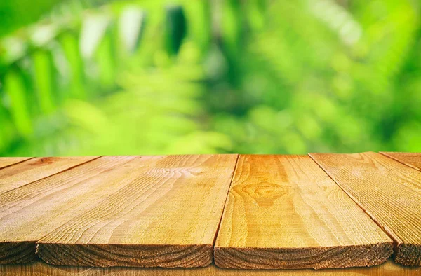 Деревянный стол перед тропическим зеленым цветочным фоном. для показа и презентации продукции. — стоковое фото
