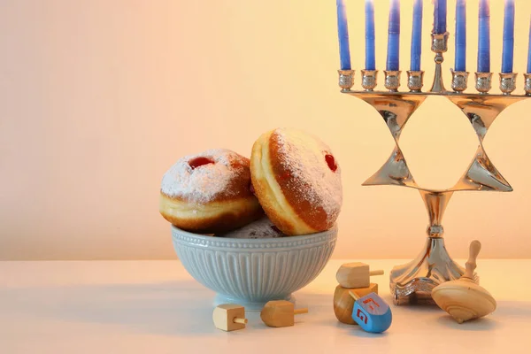 Image of jewish holiday Hanukkah background with traditional spinnig top, menorah (traditional candelabra) and donut. — Stock Photo, Image