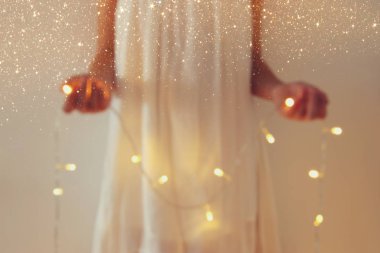 Garland Noel ışıkları tutan genç kadın soyut ve bokeh görüntüsünü.