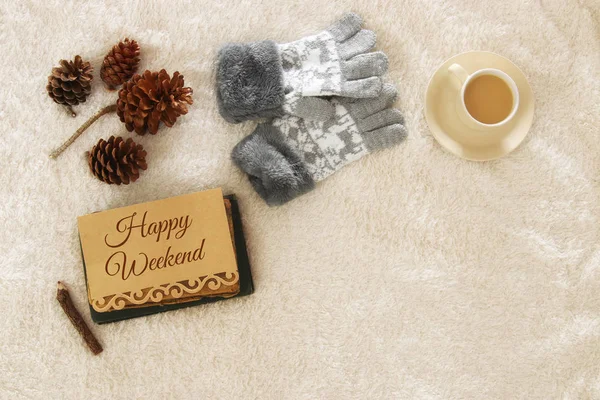 Note with text: HAPPY WEEKEND and cup of cappuccino over cozy and warm fur carpet. Top view.