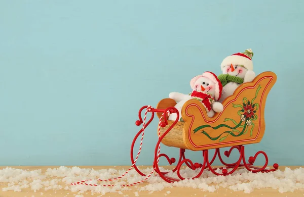Image de sapin de Noël et bonhommes de neige sur le vieux traîneau en bois sur une table en bois enneigée . — Photo
