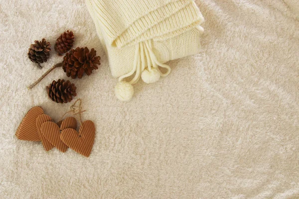 Jersey de punto, conos de pino, corazón dorado y renos sobre una alfombra acogedora y de piel. Vista superior . —  Fotos de Stock