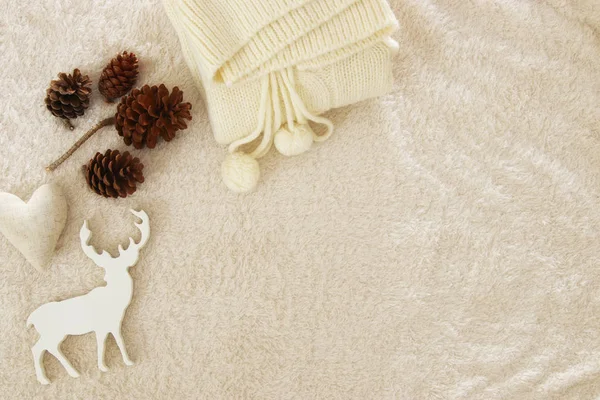 Jersey de punto, conos de pino, corazón dorado y renos sobre una alfombra acogedora y de piel. Vista superior . —  Fotos de Stock