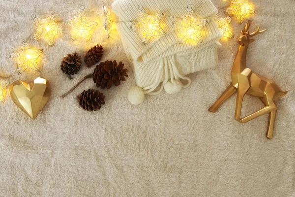 Knited sweater, pine cones, golden heart and reindeer over cozy and fur carpet. Top view. — Stock Photo, Image