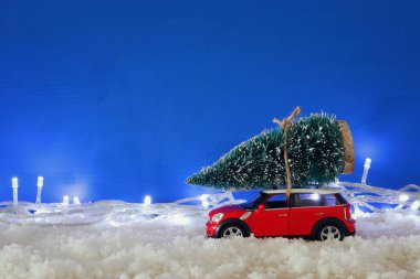 Bir Noel ağacı garland ışıkları ile kar üzerinde taşıyan kırmızı araba.