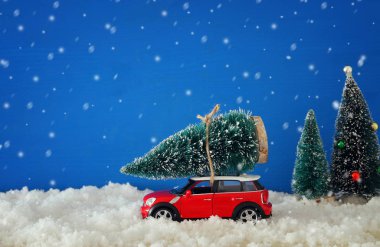 Bir Noel ağacı kar üzerinde taşıyan kırmızı araba.