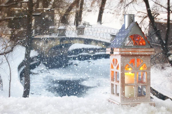 Antigua casa de madera con vela sobre la nieve y un paisaje de invierno mágico borroso fondo . — Foto de Stock