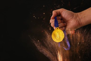 Siyah bir arka plana dayanır fireworks kaplaması ile altın madalya tutan adam el. Ödül ve zafer kavramı.