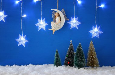 Noel ağaçları, kar taneleri çelenk ışık, peri mavi arka plan ve kar üzerine ay üzerindeki gümüş..