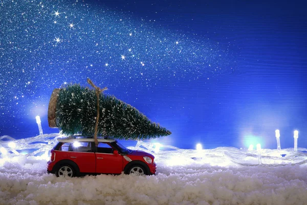 Auto rossa che trasporta un albero di Natale sulla neve . — Foto Stock