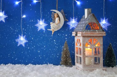 Noel ağaçları, eski fener, kar taneleri gümüş çelenk ışık, kar ve mavi arka plan üzerine ay üzerindeki peri.