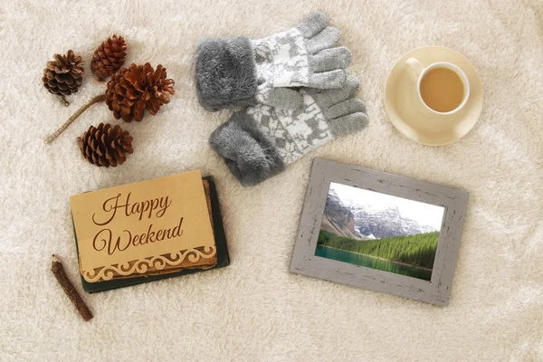 Note with text: HAPPY WEEKEND and cup of cappuccino over cozy and warm fur carpet. Top view.