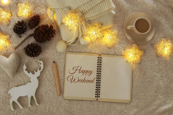 Notebook with text: ENJOY YOUR WEEKEND and cup of cappuccino over cozy and warm fur carpet. Top view. — Stock Photo, Image