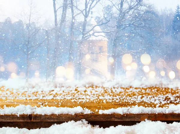 Empty table coverd with snow in front of dreamy and magical winter landscape background. For product display montage