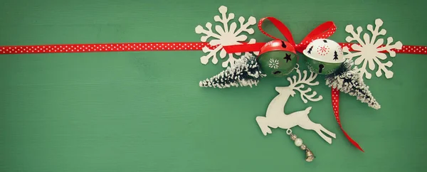 Kerstmis achtergrond met rode satijnen traditionele lint, witte herten, groenblijvende boom, papier sneeuwvlokken en jingle bells. — Stockfoto