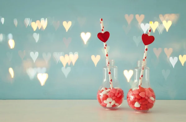 Valentijnsdag romantisch achtergrond met plastic lampje met hart vorm zoete snoepjes op witte tafel. — Stockfoto