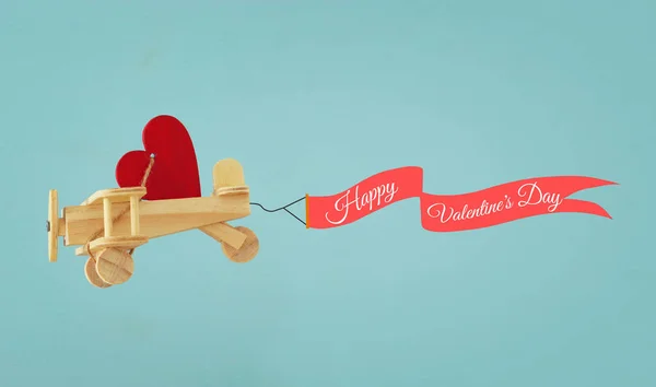 Fondo del día de San Valentín. Avión de juguete de madera con corazón y cinta volando en el cielo . —  Fotos de Stock