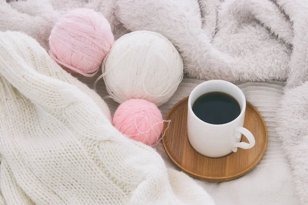 Una taza de café y bolas de lana sobre una manta blanca y acogedora. Vista superior . — Foto de Stock