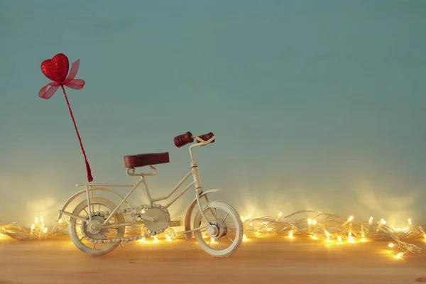 Dia dos Namorados fundo romântico com branco brinquedo de bicicleta vintage e brilho coração vermelho sobre ele sobre mesa de madeira . — Fotografia de Stock