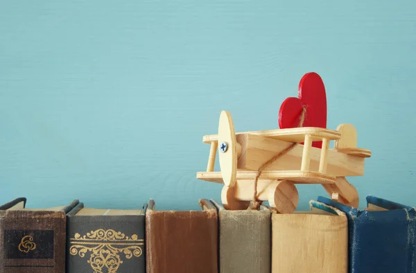 Valentine's day background. Wooden toy plane with heart over old books. — Stock Photo, Image