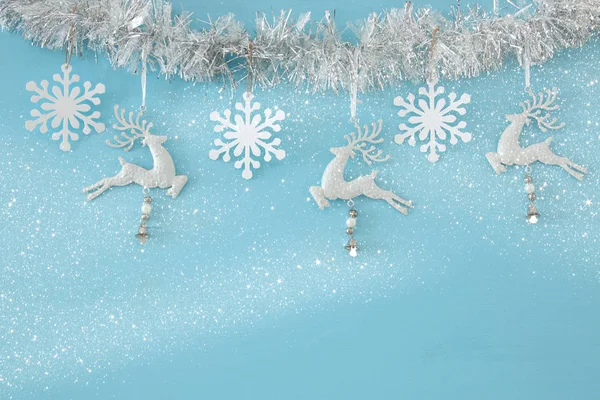 트리 축제 갈 랜드, 흰 사슴, 및 밝은 파란색 배경에 백색 종이 눈송이와 크리스마스 배경. — 스톡 사진