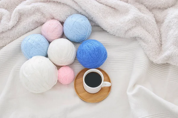 Una taza de café y bolas de lana sobre una manta blanca y acogedora. Vista superior . — Foto de Stock