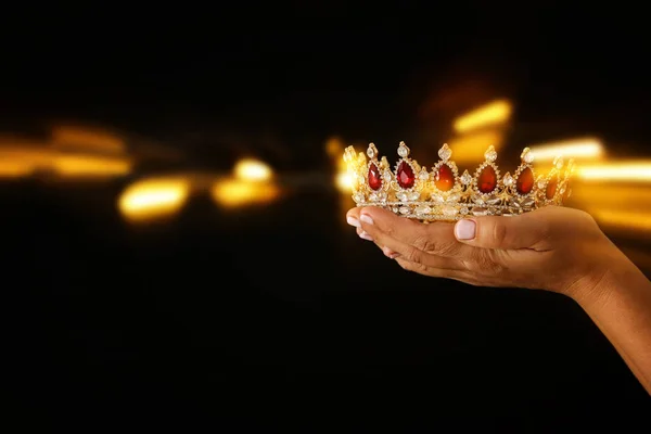 Die Hand der Frau hält eine Krone für den Showsieg oder den Gewinn des ersten Platzes. Glitzerüberzug. — Stockfoto