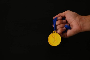 Altın madalya siyah arka planda tutan adam el. Ödül ve zafer kavramı.