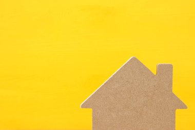 Ahşap ev modeli üzerinde sarı arka plan görüntüsü. Emlak kavramı.