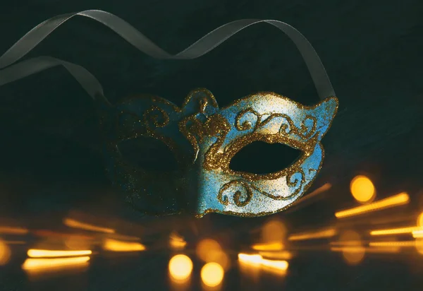 Afbeelding van elegante blauwe en gouden Venetiaanse, mardi gras mask over donkere achtergrond. Glitter overlay. — Stockfoto