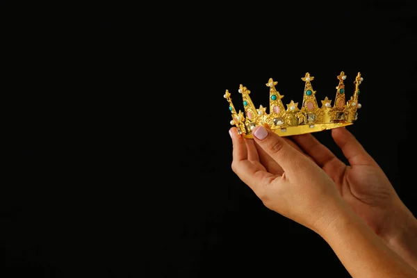 Hand van de vrouw met een kroon voor Toon overwinning of winnen eerste plaats op zwarte achtergrond. — Stockfoto
