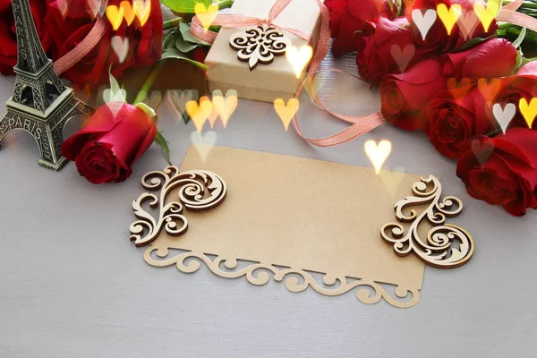 Aftelkalender voor Valentijnsdag achtergrond. Mooi boeket rozen naast lege brief op houten tafel. — Stockfoto