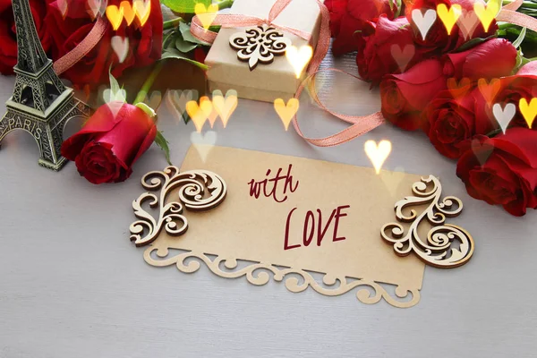 Fondo del día de San Valentín. Hermoso ramo de rosas junto a la letra con texto CON AMOR en mesa de madera . —  Fotos de Stock