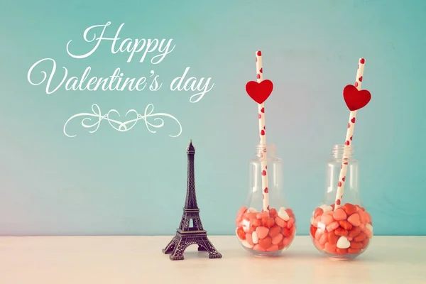 Valentine's day romantic background with plastic light bulb with heart shape sweet candies on white table. — Stock Photo, Image