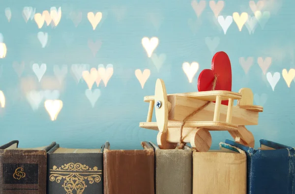 Valentine's day background. Wooden toy plane with heart over old books. — Stock Photo, Image