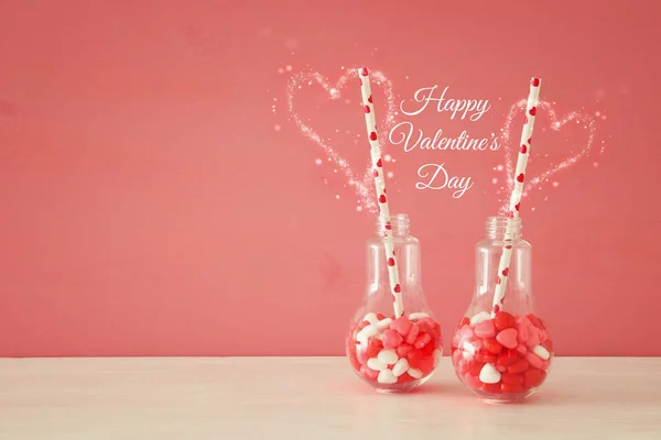 Valentine's day romantic background with plastic light bulb with heart shape sweet candies on white table. — Stock Photo, Image