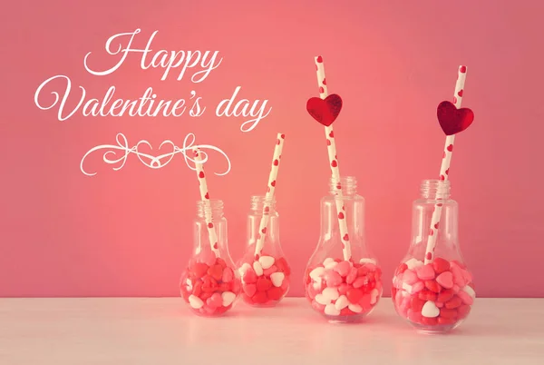 情人节浪漫背景与塑料灯泡与心脏形状甜糖果在白色桌. — 图库照片
