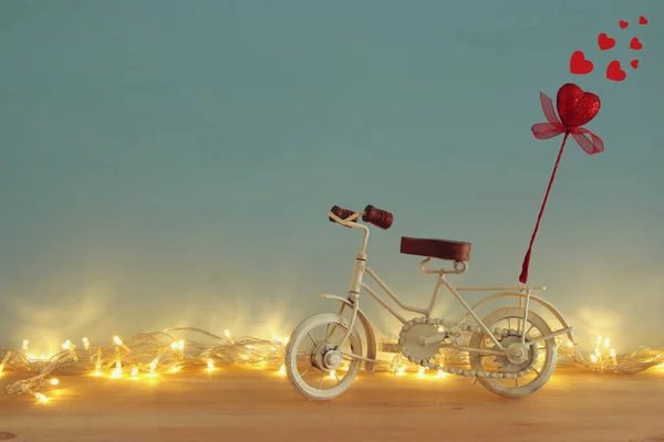 Dia dos Namorados fundo romântico com branco brinquedo de bicicleta vintage e brilho coração vermelho sobre ele sobre mesa de madeira . — Fotografia de Stock