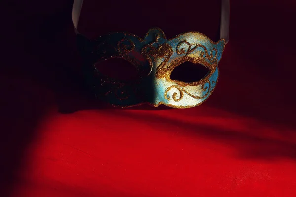 Imagen de elegante máscara veneciana azul y oro sobre fondo rojo . —  Fotos de Stock