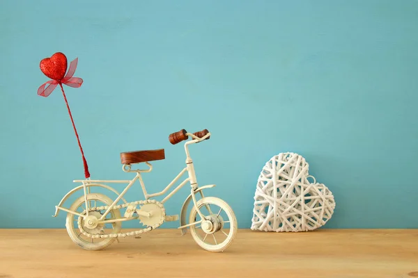 발렌타인 로맨틱 화이트 빈티지 장난감 자전거 배경과 나무 테이블에 붉은 마음 반짝. — 스톡 사진