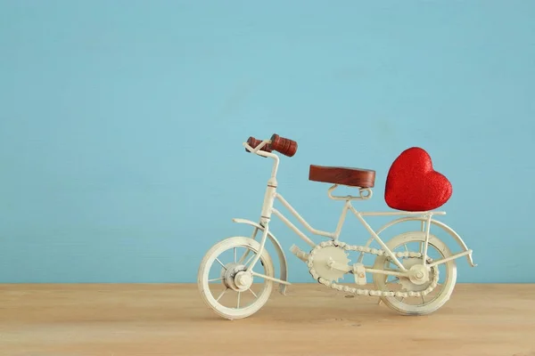 День святого Валентина романтический фон с белой винтажной велосипедной игрушкой и блеск красного сердца на нем над деревянным столом . — стоковое фото